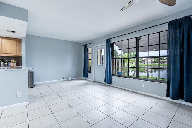 spare room featuring ceiling fan, a water view, and light tile patterned flooring