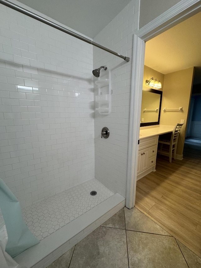 full bathroom featuring tiled shower, wood finished floors, and vanity