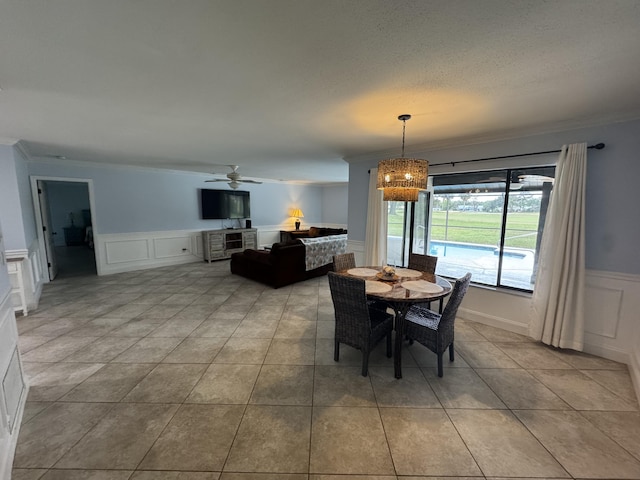 tiled dining area with crown molding and ceiling fan with notable chandelier