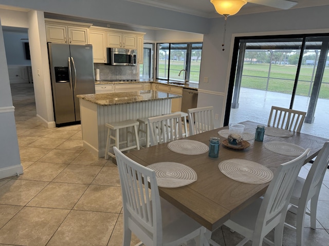 dining room featuring light tile patterned floors, ornamental molding, and sink