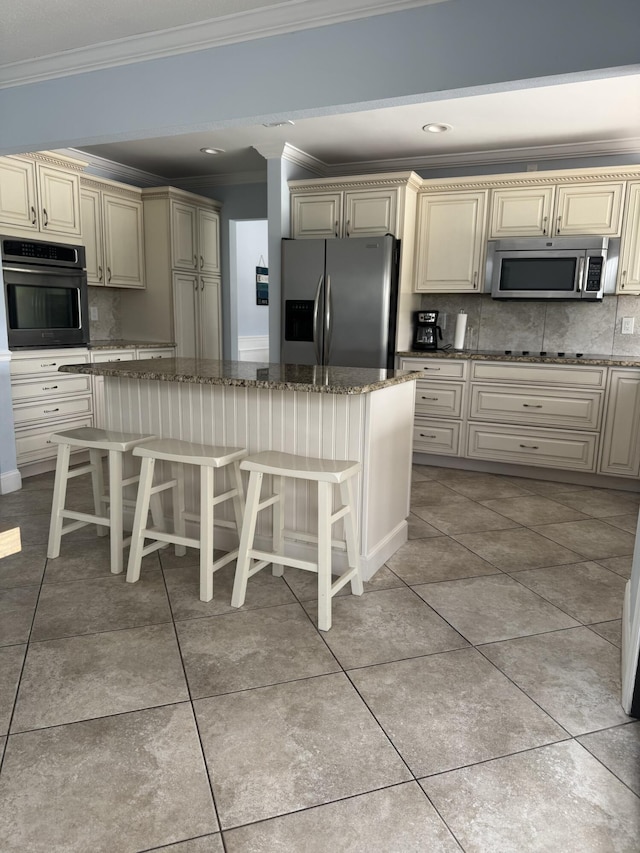 kitchen featuring stainless steel appliances, backsplash, and cream cabinets