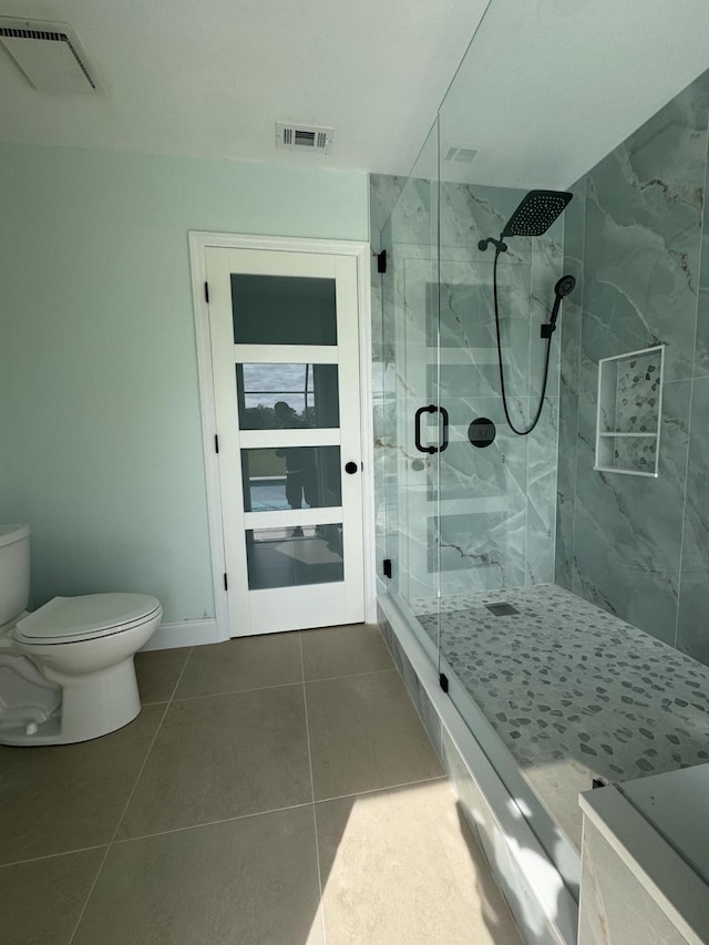 bathroom with an enclosed shower, tile patterned flooring, and toilet