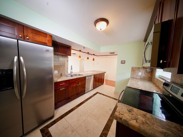 kitchen with light stone countertops, appliances with stainless steel finishes, sink, and tasteful backsplash