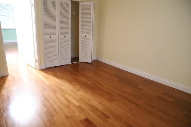 unfurnished bedroom featuring light wood-style floors, baseboards, and a closet