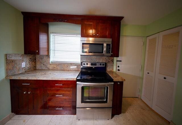 kitchen featuring light stone countertops, backsplash, stainless steel appliances, and dark brown cabinets