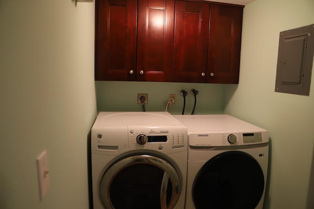 washroom with cabinet space, electric panel, and washing machine and clothes dryer