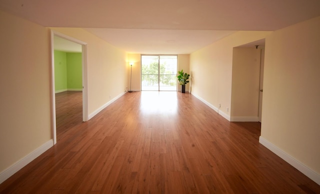 spare room with expansive windows, baseboards, and wood finished floors