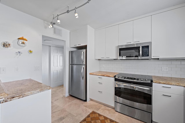 kitchen with tasteful backsplash, light tile patterned floors, appliances with stainless steel finishes, white cabinets, and light stone counters