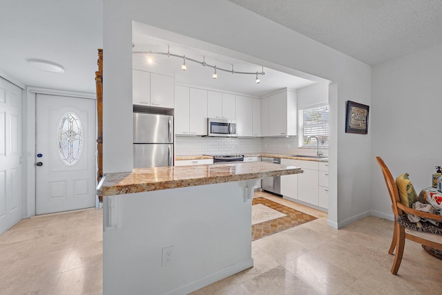 kitchen with white cabinetry, appliances with stainless steel finishes, tasteful backsplash, light stone counters, and sink