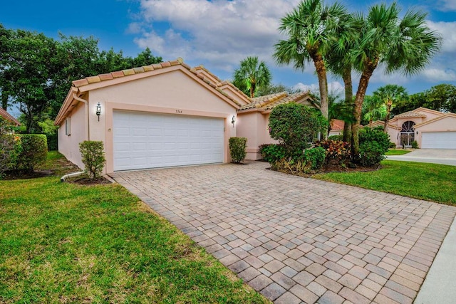 view of front of property with decorative driveway, an attached garage, a front yard, and stucco siding