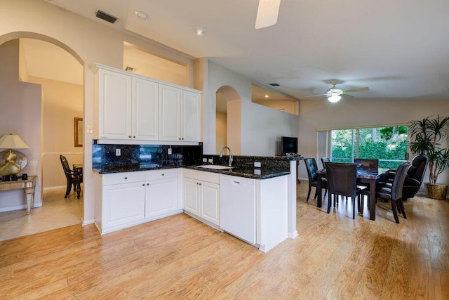 kitchen featuring white dishwasher, kitchen peninsula, and white cabinets