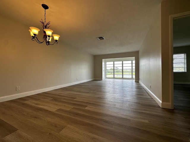 empty room featuring dark hardwood / wood-style floors and a chandelier