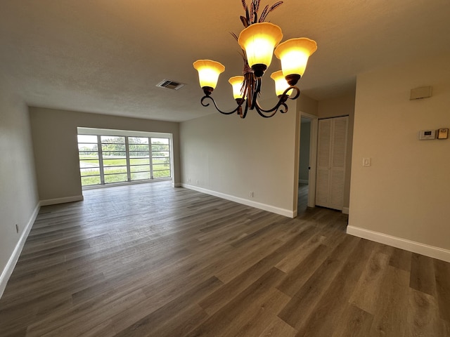 spare room featuring dark hardwood / wood-style flooring and an inviting chandelier