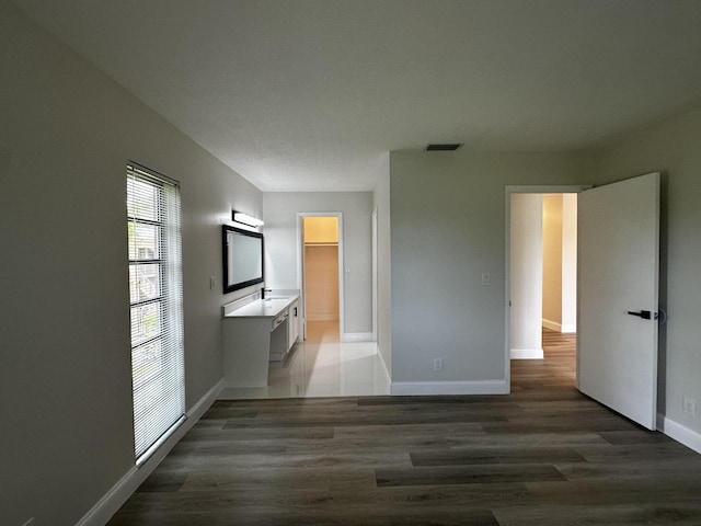 interior space featuring a walk in closet, dark wood-type flooring, and connected bathroom