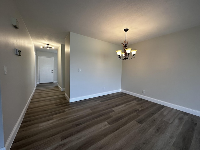 spare room with dark wood-type flooring and ceiling fan with notable chandelier