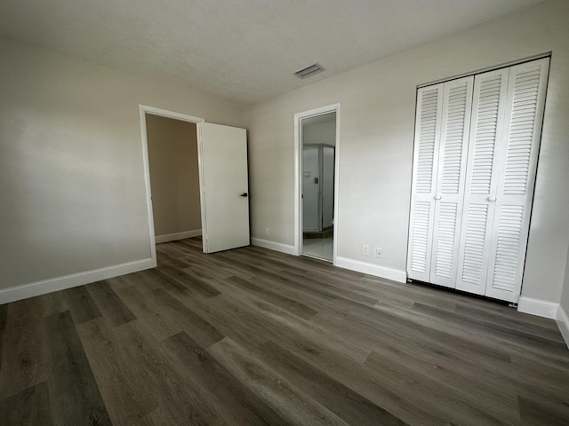 unfurnished bedroom featuring a closet, dark hardwood / wood-style floors, and connected bathroom