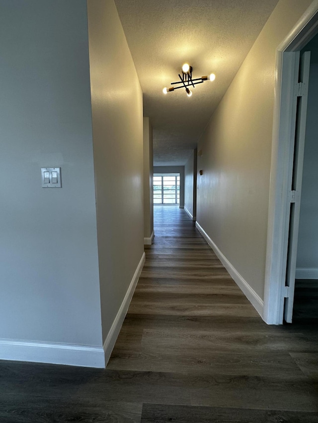 hall with dark wood-type flooring and a textured ceiling