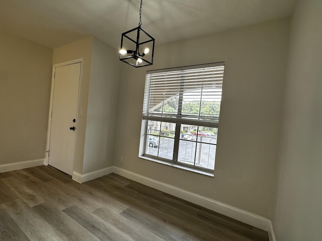 unfurnished dining area featuring wood-type flooring and a notable chandelier