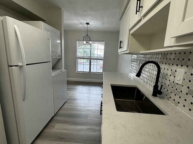 kitchen with tasteful backsplash, white cabinets, sink, and white fridge