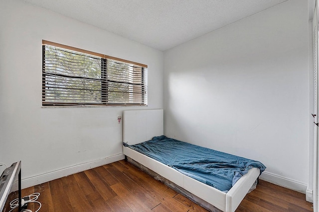 bedroom with a textured ceiling and dark hardwood / wood-style floors