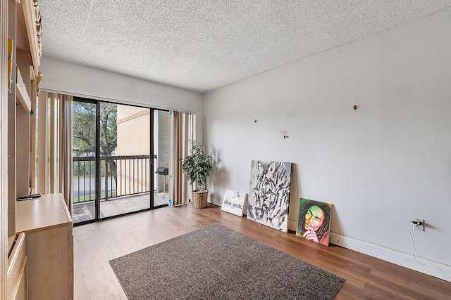 unfurnished room with hardwood / wood-style floors and a textured ceiling