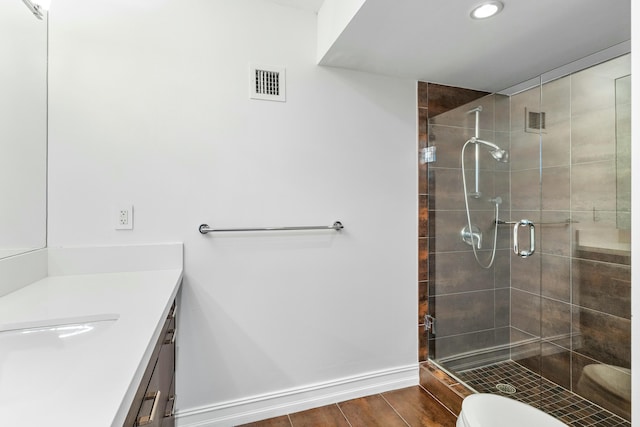 bathroom with a shower with shower door, vanity, and toilet