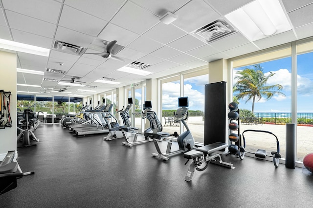 gym featuring a paneled ceiling and a wall of windows