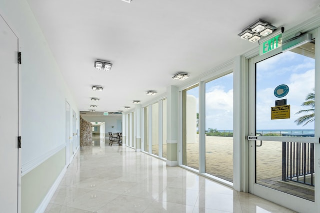 corridor featuring a water view, light tile patterned flooring, and floor to ceiling windows