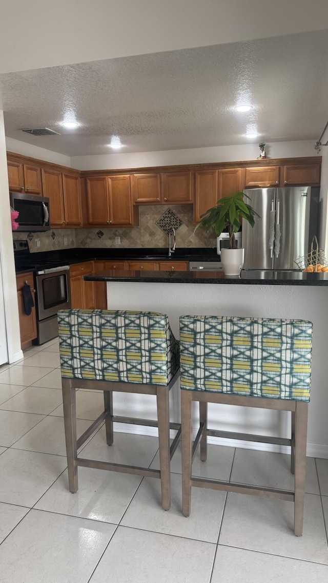 kitchen with sink, stainless steel appliances, a textured ceiling, and light tile patterned flooring