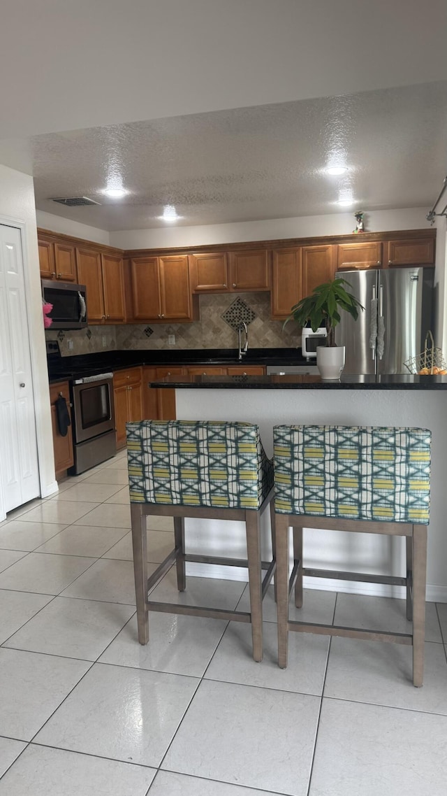 kitchen featuring stainless steel appliances, decorative backsplash, and light tile patterned floors