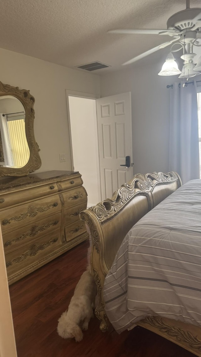 bedroom featuring a textured ceiling, dark wood-type flooring, and ceiling fan