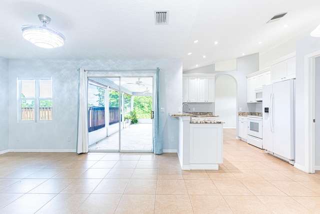 kitchen with light stone countertops, light tile patterned floors, white cabinets, and white appliances