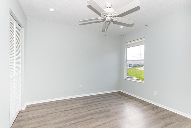 unfurnished bedroom with ceiling fan, wood-type flooring, a closet, and a textured ceiling