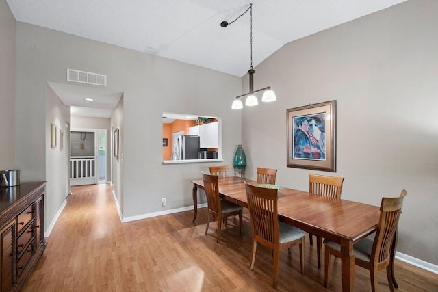 dining room featuring lofted ceiling and light hardwood / wood-style floors