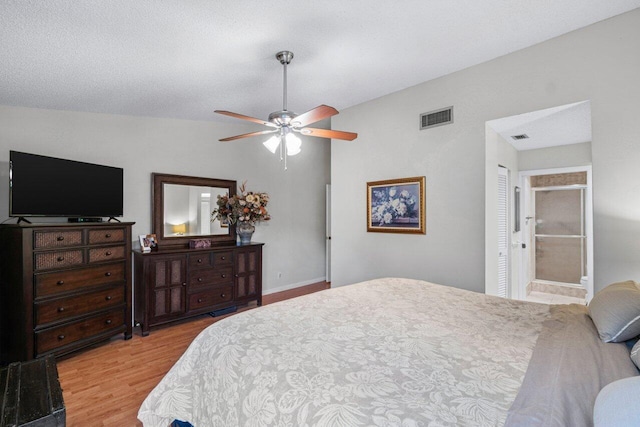 bedroom featuring ceiling fan, a textured ceiling, light hardwood / wood-style flooring, and ensuite bath