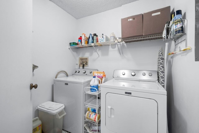 clothes washing area with washing machine and dryer and a textured ceiling