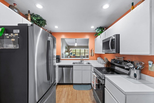 kitchen with light wood-type flooring, stainless steel appliances, white cabinetry, and sink