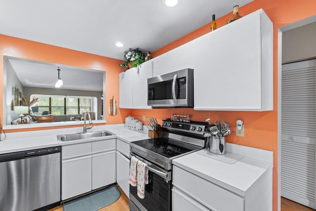 kitchen with decorative light fixtures, sink, white cabinetry, and appliances with stainless steel finishes