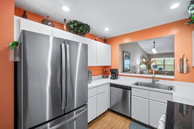 kitchen with light wood-type flooring, appliances with stainless steel finishes, white cabinetry, and hanging light fixtures