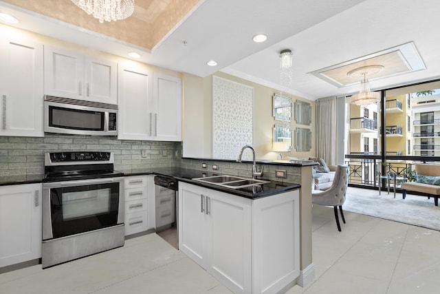 kitchen with white cabinetry, appliances with stainless steel finishes, kitchen peninsula, and hanging light fixtures