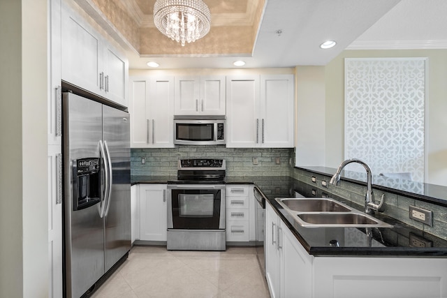 kitchen featuring stainless steel appliances, white cabinetry, a tray ceiling, and sink