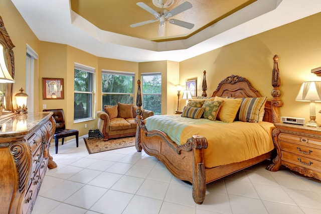 tiled bedroom featuring ceiling fan and a raised ceiling