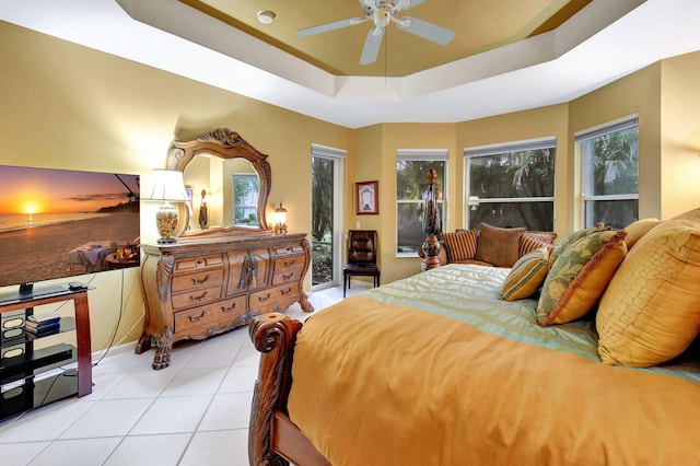 bedroom with ceiling fan, a raised ceiling, and light tile patterned floors