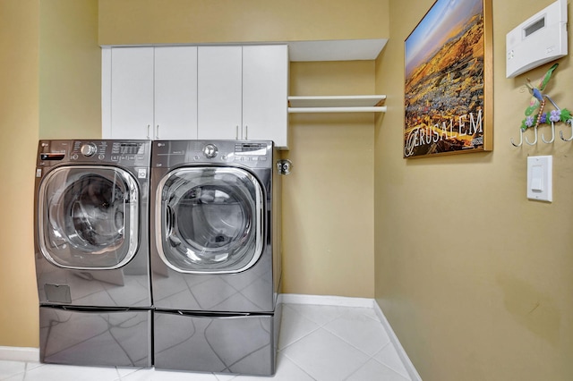 washroom with cabinets, light tile patterned floors, and washing machine and clothes dryer