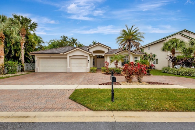 view of front of home with a tiled roof, an attached garage, decorative driveway, and stucco siding