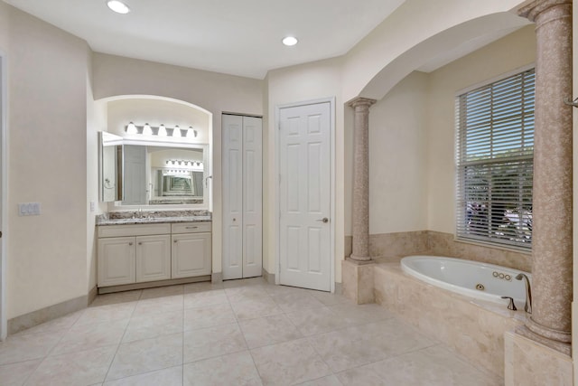 bathroom with tiled bath, tile patterned floors, vanity, and decorative columns