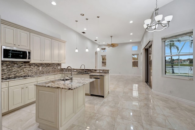 kitchen featuring light stone counters, sink, pendant lighting, and appliances with stainless steel finishes