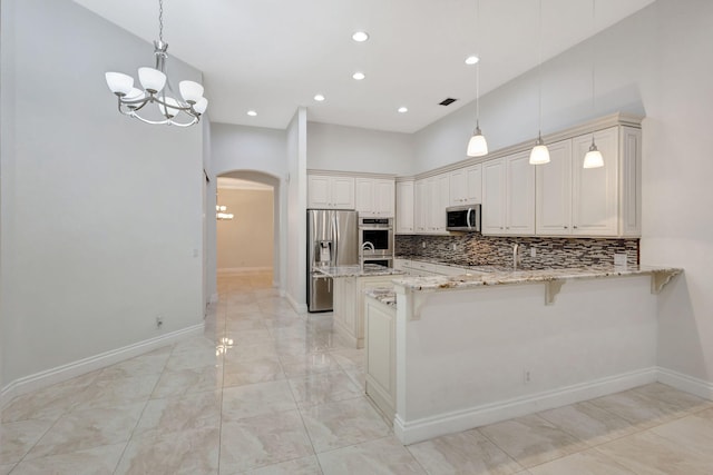 kitchen featuring pendant lighting, a breakfast bar, kitchen peninsula, light stone countertops, and stainless steel appliances