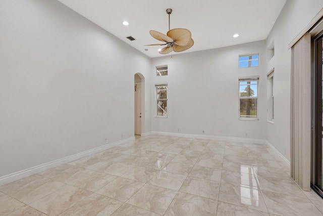 unfurnished room with ceiling fan and a high ceiling