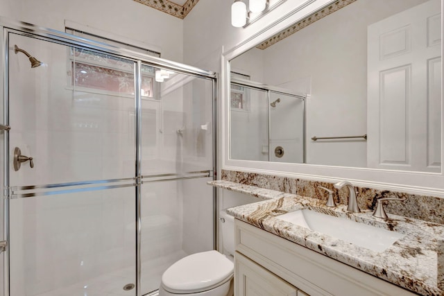 bathroom featuring toilet, vanity, and a shower with door